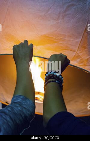 Il rilascio di una luce di lanterna durante il Loy Krathong festival in Chiang Mai, chiudere l immagine di mani Foto Stock