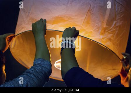 Il rilascio di una luce di lanterna durante il Loy Krathong festival in Chiang Mai, chiudere l immagine di mani Foto Stock