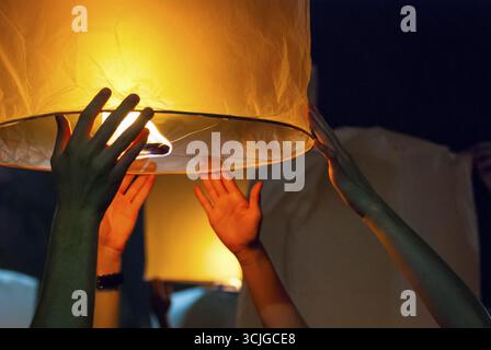 Il rilascio di una luce di lanterna durante il Loy Krathong festival in Chiang Mai, chiudere l immagine di mani Foto Stock