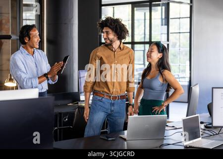 Team aziendale che collabora in un ufficio moderno, discutendo il progetto con entusiasmo Foto Stock