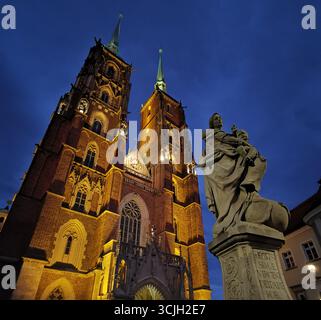 Cattedrale di San Giovanni Battista con guglie gemelle illuminate di notte, Wrocław. Primo piano: Statua barocca, Ostrów Tumski, Isola della Cattedrale. Foto Stock