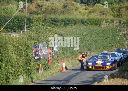 Auto d'epoca su strada panoramica in mezzo all'evento Motorsport con striscioni e appassionati. Shere Hill Climb, East Clandon, Guildford Foto Stock