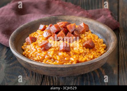 Risotto sostanzioso con chorizo, pomodori maturi ed erbe aromatiche servito in un rustico recipiente in ceramica Foto Stock