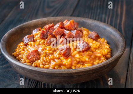 Risotto sostanzioso con chorizo, pomodori maturi ed erbe aromatiche servito in un rustico recipiente in ceramica Foto Stock