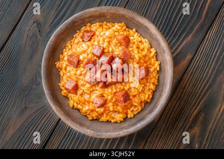 Risotto sostanzioso con chorizo, pomodori maturi ed erbe aromatiche servito in un rustico recipiente in ceramica Foto Stock