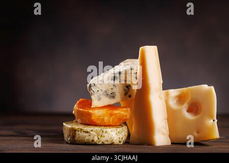Formaggi assortiti di forme e consistenze diverse, esposti insieme su una superficie rustica Foto Stock