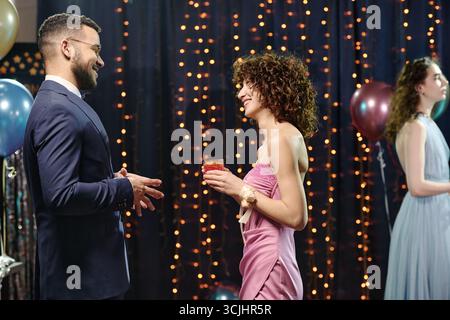 Giovane uomo caucasico che parla con la giovane donna caucasica al Partito formale Foto Stock