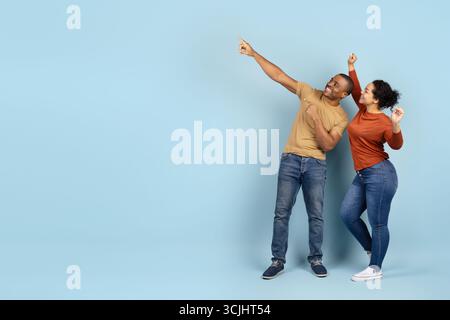 Gioiosa coppia afroamericana che punta verso l'alto con entusiasmo Foto Stock