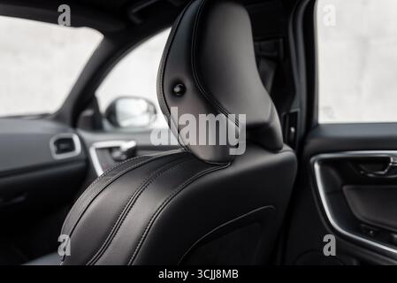 Sedile anteriore con poggiatesta nelle vetture moderne - vista posteriore di tre quarti. Sedile in pelle interno della vettura - immagine ravvicinata. Sedile anteriore nero di un'auto di medie dimensioni a fuoco Foto Stock