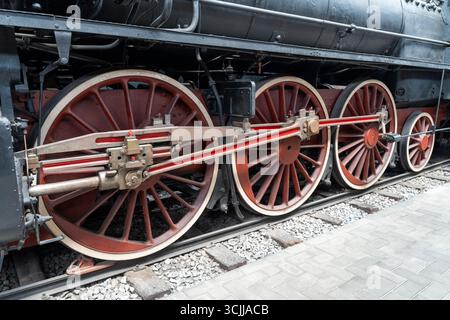Vista ravvicinata delle ruote delle locomotive a vapore e delle aste di trasmissione meccaniche Foto Stock