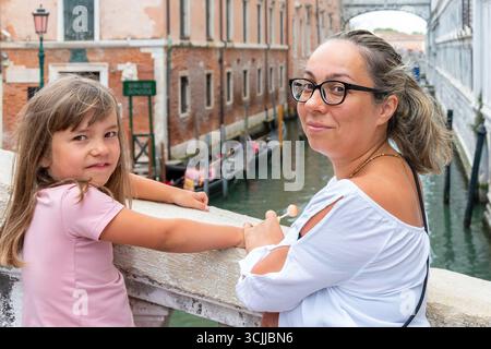 Madre e figlia in piedi su un ponte a Venezia, sorridendo alla telecamera, primo piano Foto Stock