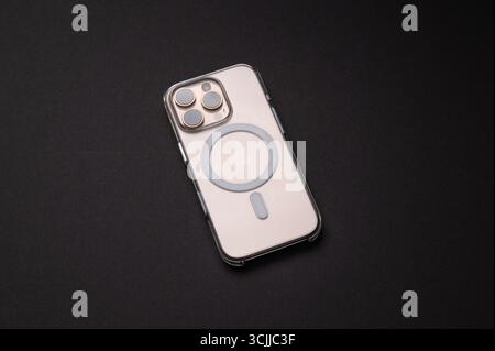 Magonza, Germania - 07 settembre 2025: Smartphone iPhone 16 Pro alloggiato in una custodia trasparente con protezione magnetica si appoggia su uno sfondo scuro. Foto Stock