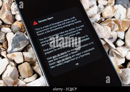 Messaggio di prova degli avvisi di emergenza sul telefono cellulare posizionato su pietre di ghiaia. Stafford, Regno Unito, 7 settembre 2025 Foto Stock