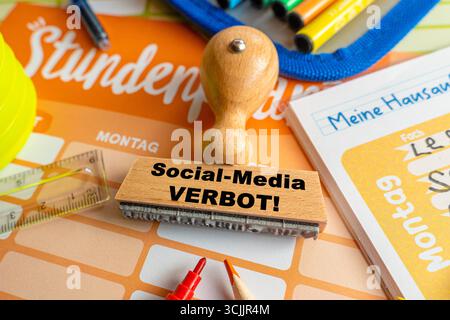 Baviera, Germania - 3 settembre 2025: FOTOMONTAGGIO, Un francobollo con l'iscrizione: Divieto dei social media, è su un orario *** FOTOMONTAGE, Ein Stempel mit der Aufschrift: Social-Media Verbot, liegt auf einem Stundenplan Foto Stock