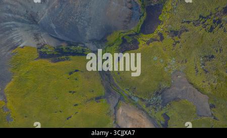 Ripresa aerea della natura selvaggia islandese con tortuose insenature macchie di muschio e terreno vulcanico che si fondono in un paesaggio naturale colorato Foto Stock