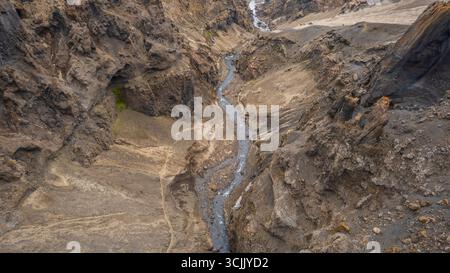 Stretto canyon con ripide scogliere rocciose e un fiume tortuoso che attraversa l'arido paesaggio vulcanico dell'Islanda Foto Stock