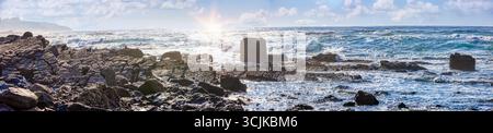 Tramonto sull'oceano Atlantico, mare con onde, spiaggia naturale con grandi rocce Foto Stock