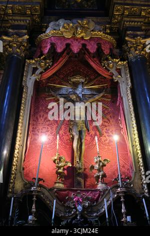 Gesù Cristo su una croce con cortina rossa di sangue, fondo tessile. Alla Basilica di Santa Maria dei Servi. A Bologna, Italia. Foto Stock
