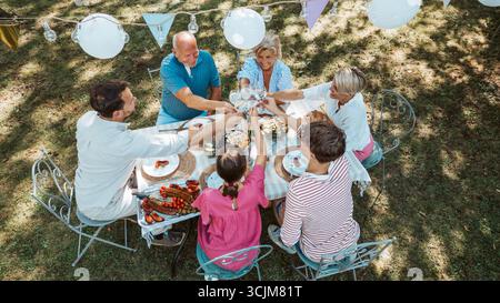 Vista aerea del brindisi multigenerazionale in famiglia durante la festa al barbecue all'aperto. Foto Stock