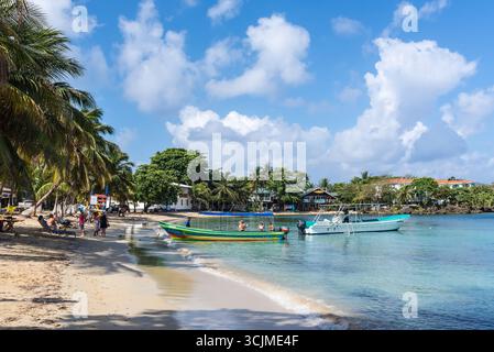 Isla de Roatan, Honduras - 16 aprile 2024: Spiaggia di Half Moon Bay con molo e barche sull'isola di Roatan, Honduras. Foto Stock
