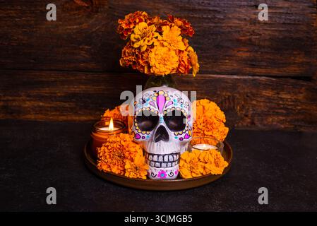 Teschio dipinto con fiori cempasuchil o calendula e candele, altare per la vacanza messicana dia De Los Muertos su sfondo di legno scuro. Giorno del Dea Foto Stock