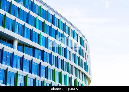 Facciata colorata di un edificio di uffici con pannelli di finestre angolati in una disposizione geometrica verde, viola e blu. Foto Stock