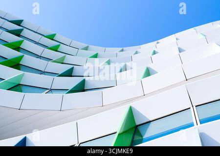 Facciata colorata di un edificio di uffici con pannelli di finestre angolati in una disposizione geometrica verde, viola e blu. Foto Stock