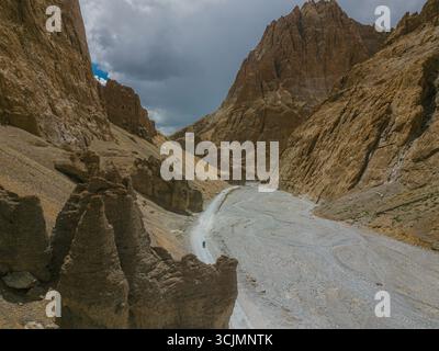 Vista aerea del terreno aspro e soleggiato e delle aspre montagne si incontrano con il cielo in una sinfonia di toni terrosi, Zanskar, Ladakh, India. Foto Stock