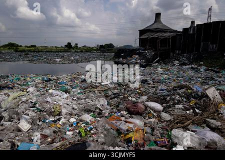 Dacca, Dacca, Bangladesh. 8 settembre 2025. Camini pieni di fumo dominano il paesaggio presso il sito in fiamme, un simbolo minaccioso del costo ambientale e umano. Nella periferia di Dacca, Bangladesh, i lavoratori informali del riciclaggio sopportano condizioni pericolose per estrarre materiali riutilizzabili da fogli di alluminio. Questo processo comporta la combustione di fogli di alluminio raccolti da flussi di rifiuti industriali e domestici in camini improvvisati. Tale pratica, pur fornendo un sostentamento ai lavoratori, comporta rischi significativi sia per la salute umana che per l'ambiente a causa delle emissioni tossiche e dell'assenza di misure di sicurezza. Foto Stock