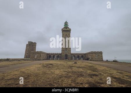 Vista del maestoso faro che si erge alto sulla costa frastagliata, le sue pietre intemprate che sussurrano storie del mare, Phare du Cap Frehel, Bretagne, Francia. Foto Stock