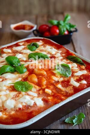 Gnocchi alla sorrentina cotti in padella, con basilico fresco, pomodori ciliegini e ricca salsa di pomodoro, che incarna la tradizionale cucina napoletana Foto Stock
