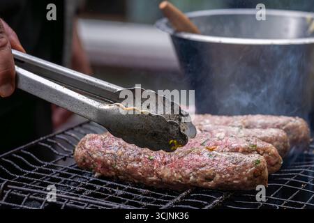 Cuocere alla griglia il kofta di agnello arabo al caldo del carbone. Gustosi bastoncini di kofta arabi su una griglia a carbone calda. Kebab kofta di agnello cotti sopra le fiamme calde del carbone Foto Stock