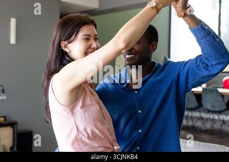 Coppia che balla gioiosamente a casa, festeggiando insieme con sorrisi e risate Foto Stock