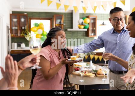 La candela soffiata sul cupcake, una donna anziana gioiosa che festeggia il compleanno con gli amici Foto Stock