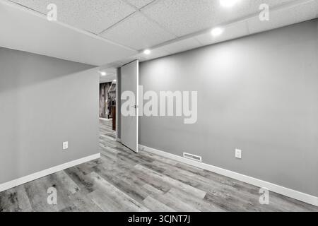 Camera bianca con una porta e un cartello sul muro. La stanza è vuota. Ci sono due interruttori sulla parete Foto Stock