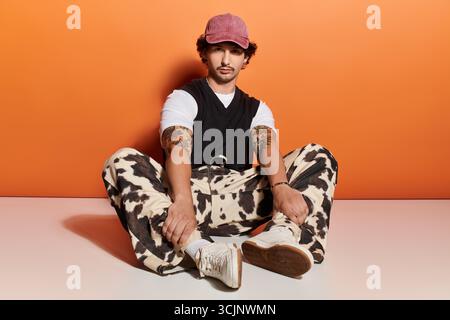 Giovane uomo alla moda in una posa rilassata, sfoggiando il suo stile e il suo atteggiamento. Foto Stock