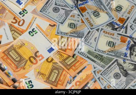 Banconote miste da 100 dollari USA e banconote da 50 euro si diffondono su una tavola creando un contesto finanziario e patrimoniale. Foto Stock