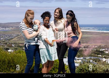 Amici che festeggiano all'aperto con polvere colorata, godendosi momenti di gioia insieme Foto Stock