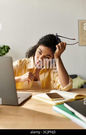 Una giovane donna afro-americana si impegna con cura nel lavoro a distanza dal suo ambiente elegante di casa. Foto Stock