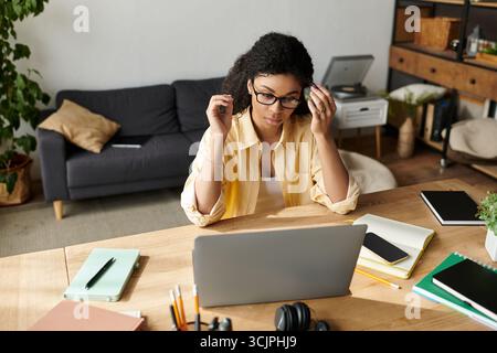 Una giovane donna afroamericana si impegna diligentemente in un lavoro a distanza nel suo elegante appartamento. Foto Stock