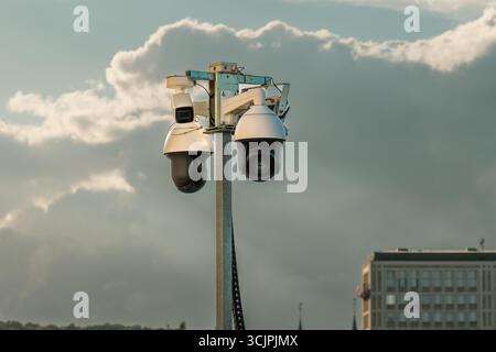 Telecamere di sorveglianza Urban Security Pole City background. Set di moderne telecamere a circuito chiuso montate su un palo metallico contro un cielo nuvoloso in un ambiente urbano Foto Stock