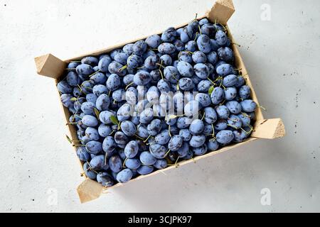 Prugne fresche biologiche e mature in scatola di legno Foto Stock