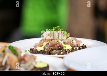 Tartaro di pesce (ide) su pane nero tostato. Tartaro di pesce crudo servito con pane di segale sul piatto. Tartaro di pesce gourmet. Foto Stock