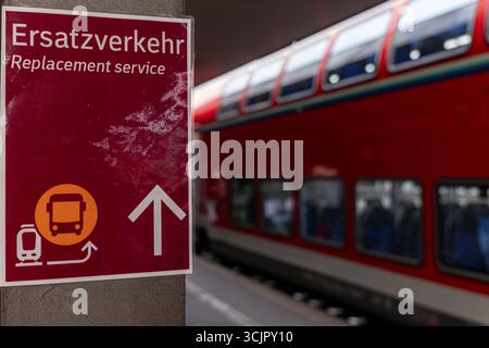 Ersatzverkehr am Bahnhof Hinweisschild zum Schienenersatzverkehr 08.09.25, Selters: Symbolfoto, Illustrationsbild, Symbolbild, Illustrationsfoto, Alltagsszene Ein Schild am Bahnsteig weist auf den Ersatzverkehr Hin. Der Hinweis in Deutsch und Englisch informiert Fahrgäste über den Schienenersatzverkehr servizio di sostituzione mit Bussen. Im Hintergrund ist unscharf ein roter Doppelstockzug der Deutschen Bahn zu sehen. Limburg Hessen Deutschland *** servizio di sostituzione alla stazione cartello per il servizio di sostituzione della ferrovia 08 09 25, foto simbolo Selter, foto illustrazione, immagine simbolo, foto illustrazione Foto Stock