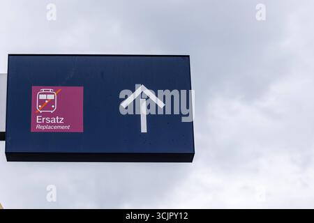 Hinweisschild Ersatzverkehr am Bahnhof 08.09.25, Selters: Symbolfoto, Illustrationsbild, Symbolbild, Illustrationsfoto, Alltagsszene Ein Schild am Bahnhof weist den Weg zum Ersatzverkehr. DAS Piktogramm mit durchgestrichenem Zug und der Hinweis Ersatz / Replacement machen deutlich, dass ein Schienenersatzverkehr eingerichtet ist. Rechts daneben zeigt ein Weißer Pfeil nach oben. Der Himmel ist grau und bewölkt. Limburg Hessen Deutschland *** servizio di sostituzione segnaletica alla stazione ferroviaria 08 09 25, foto simbolo Selter, immagine illustrazione, immagine simbolo, foto illustrazione, la scena di tutti i giorni È Un segnale Foto Stock
