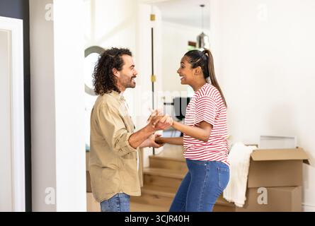 Ballare insieme, coppia felice e diversificata che condivide momenti di gioia a casa Foto Stock