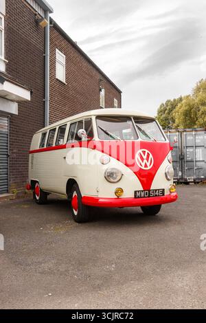Classico camper vintage Volkswagen tipo 2 (tipo 1), rosso e bianco, con schermo diviso, parcheggiato da container industriali, giorno coperto newcastle uk Foto Stock