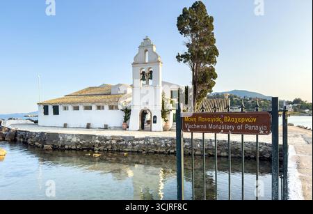 Vlachernon Monastero di Panayia, insegna lingua greca e inglese. Pareti bianche e edificio del campanile nell'isola di Corfù, Grecia. Foto Stock