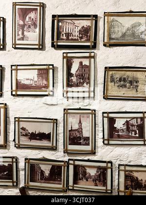 Tarnopil, Ucraina - 10 agosto 2025: Una collezione di vecchie fotografie in cornici dorate montate su una parete testurizzata. Foto Stock