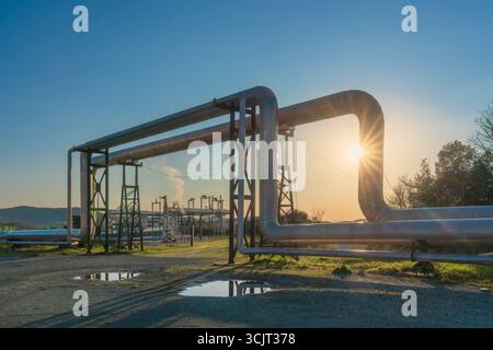 Gasdotti di una centrale geotermica al tramonto a Larderello, Toscana, Italia. L'energia geotermica è una forma di energia alternativa e sostenibile Foto Stock